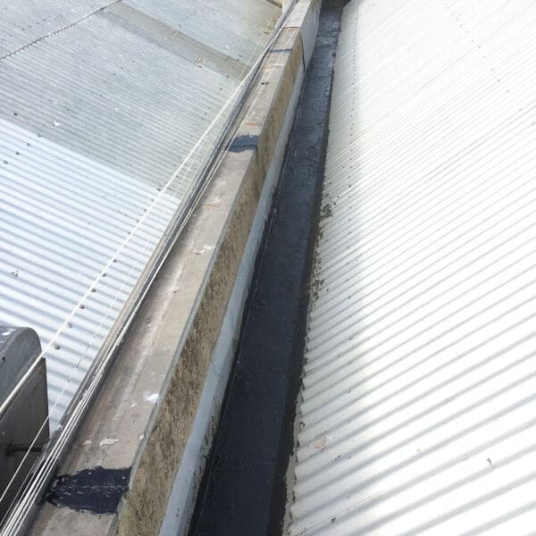 A corrugated steel roof with a repaired and sealed box gutter