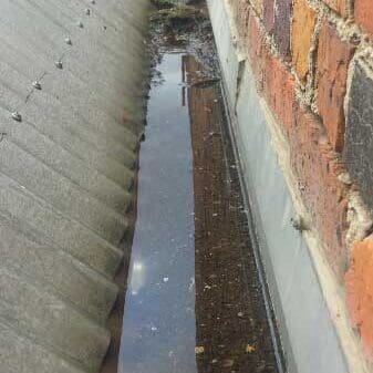 Corrugated rof sheets meeting a box gutter pooling with water
