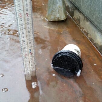 A used coffee cup floating in the water that floods a box gutter