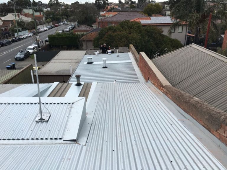 A commercial steel roof with corrugated metal sheets and flues